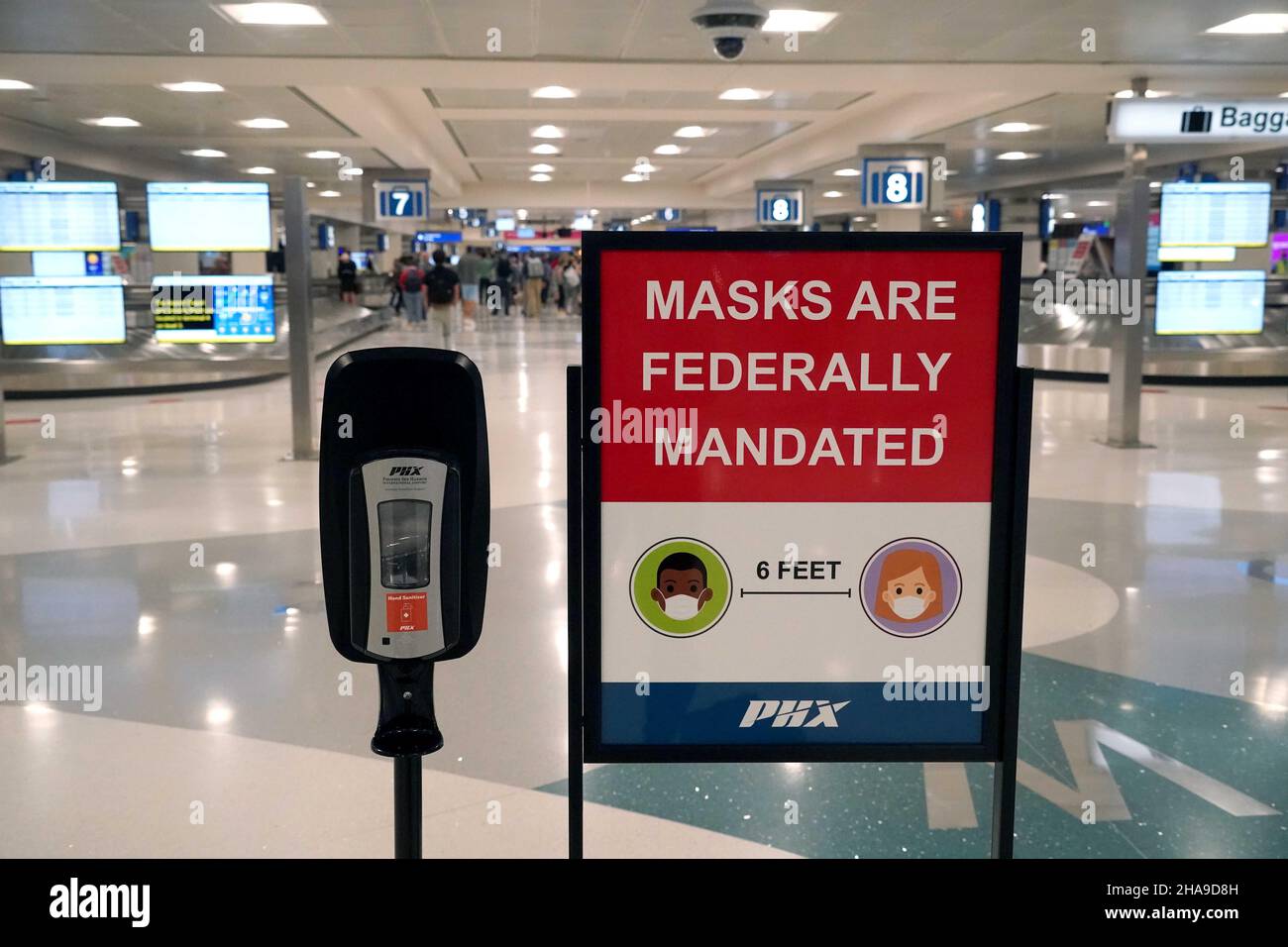 Un panneau d'avertissement de mandat de masque fédéral et un distributeur de désinfectant pour les mains dans la zone de retrait des bagages du terminal 4 de l'aéroport international de Sky Harbor, Tuesda Banque D'Images