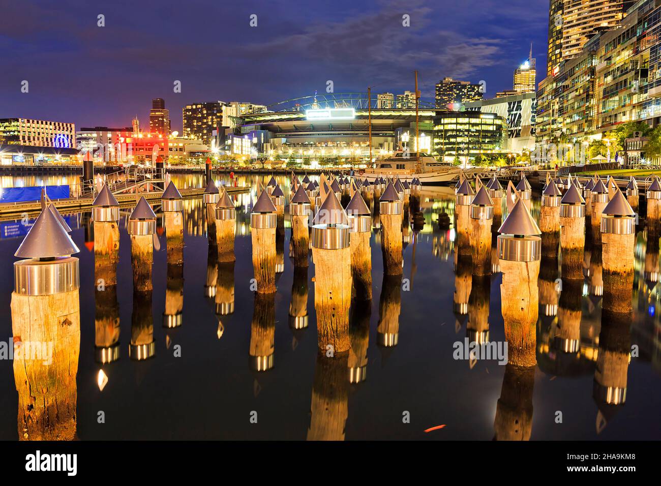 des têtes de poteaux en bois de fer dans la banlieue des Docklands de Melbourne au coucher du soleil - reflets pittoresques du quai historique et lumières de la ville. Banque D'Images