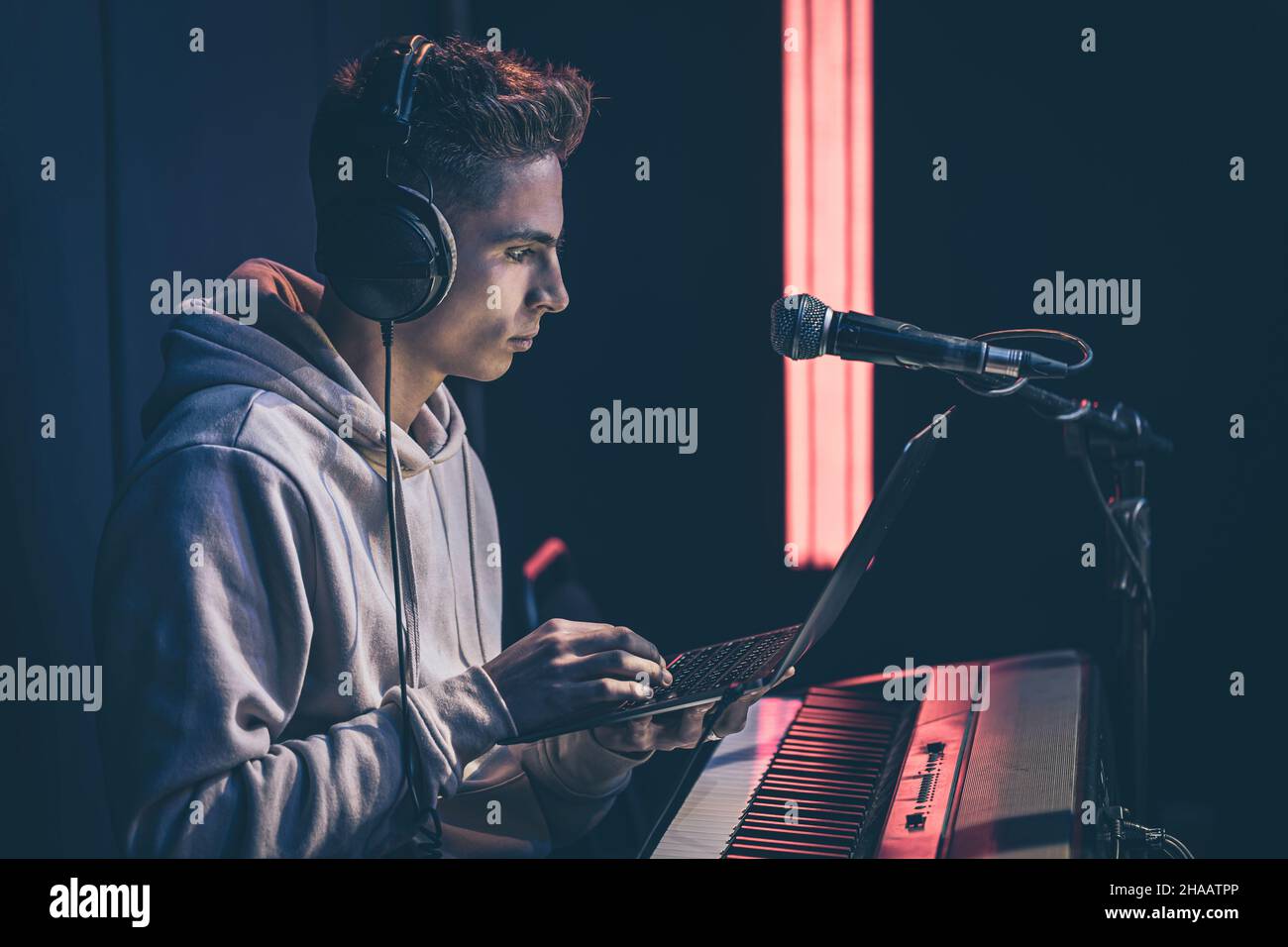 Jeune homme dans un casque derrière les clés musicales avec un ordinateur portable. Banque D'Images