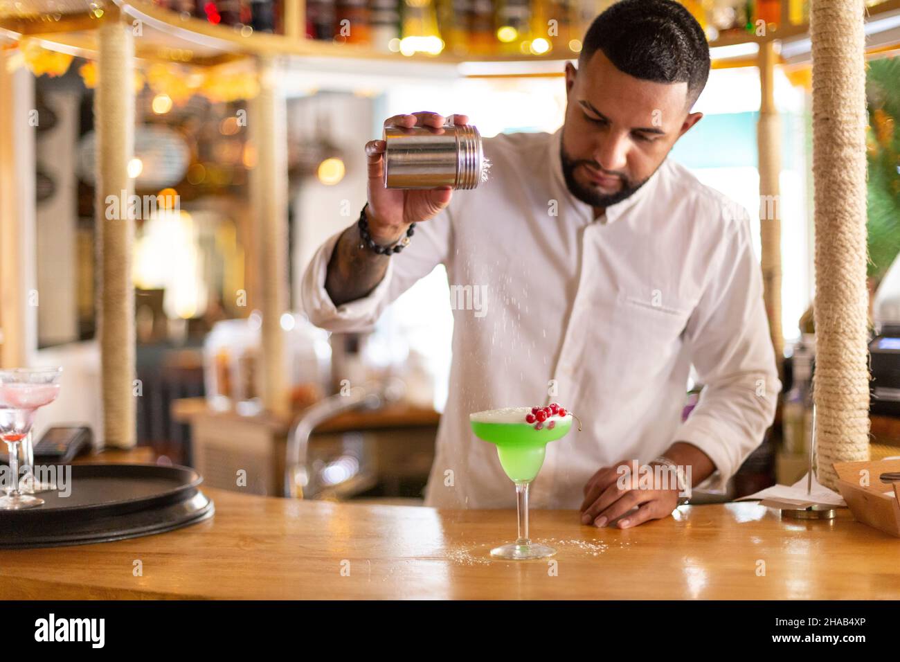 Un jeune latino prépare avec soin une boisson alcoolisée dans un bar à cocktails moderne.Espace pour le texte.Mise au point sélective. Banque D'Images