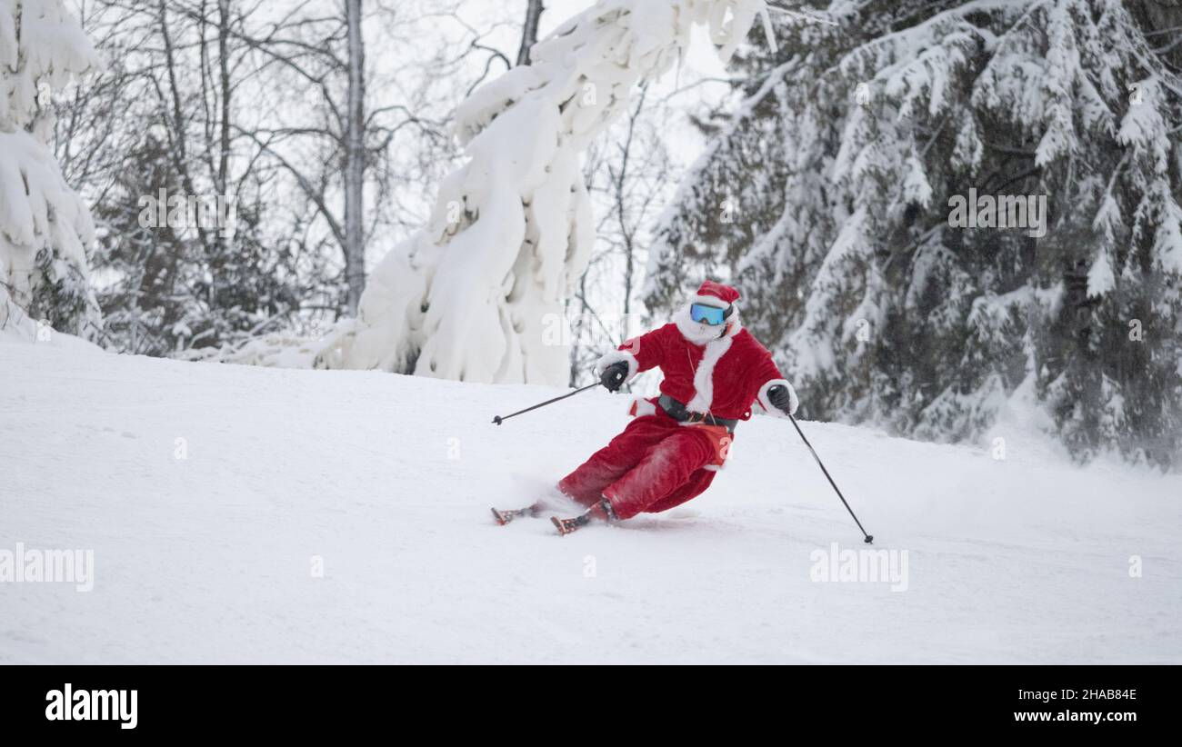 Santa Claus ski alpin ski alpin dans la forêt enneigée station de ski pente Noël sport fête du style de vie Banque D'Images