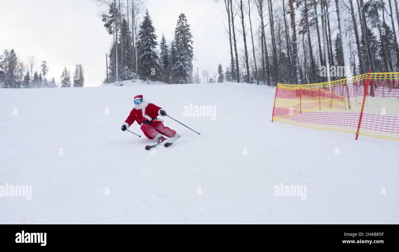 Santa Claus ski alpin ski alpin dans la forêt enneigée station de ski pente Noël sport fête du style de vie Banque D'Images