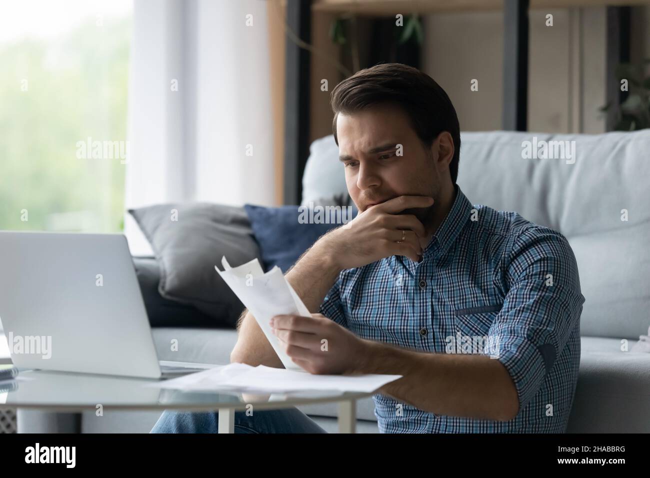 L'homme tient des chèques se sent stressé en raison du manque d'argent Banque D'Images