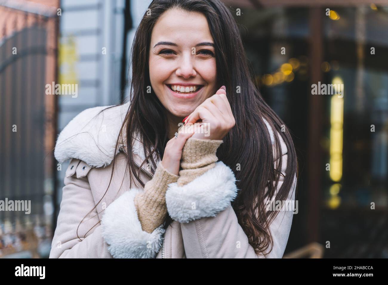 Belle femme souriante avec de longs cheveux portant veste chaude marcher dans la rue chaud hiver européen Banque D'Images