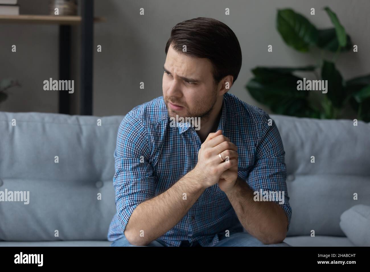 Homme souffrant de douleur mentale, asseyez-vous sur le canapé regarde à distance Banque D'Images