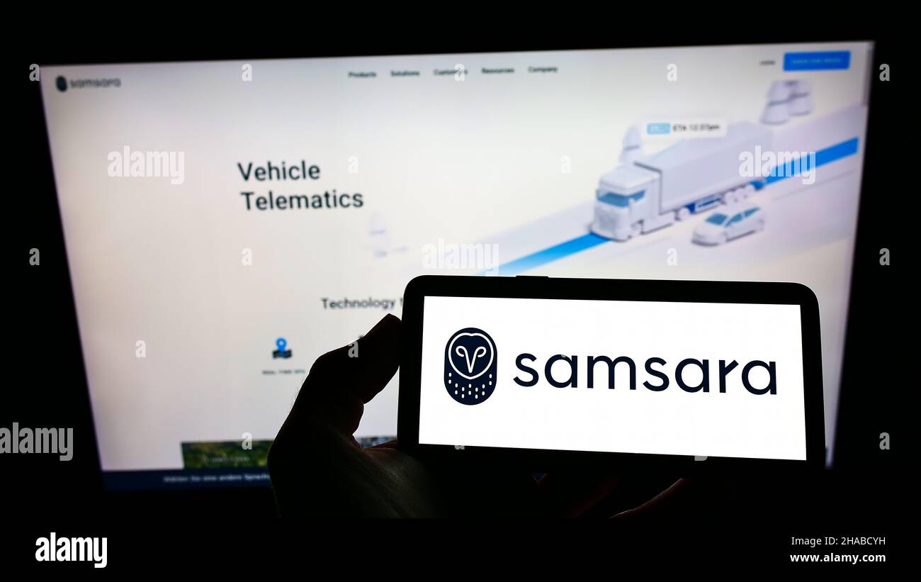 Personne tenant un téléphone mobile avec le logo de la société américaine de logiciel de cloud Samsara Inc. À l'écran en face de la page Web.Mise au point sur l'affichage du téléphone. Banque D'Images