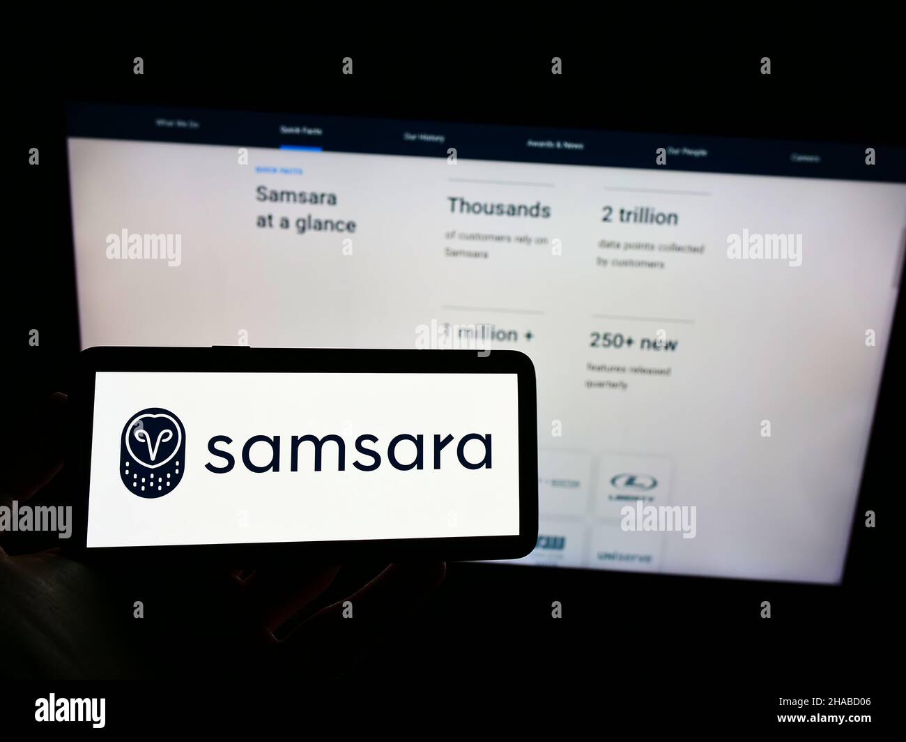 Personne tenant un téléphone portable avec le logo de la société américaine de logiciel de cloud Samsara Inc. À l'écran en face de la page Web d'affaires.Mise au point sur l'affichage du téléphone. Banque D'Images