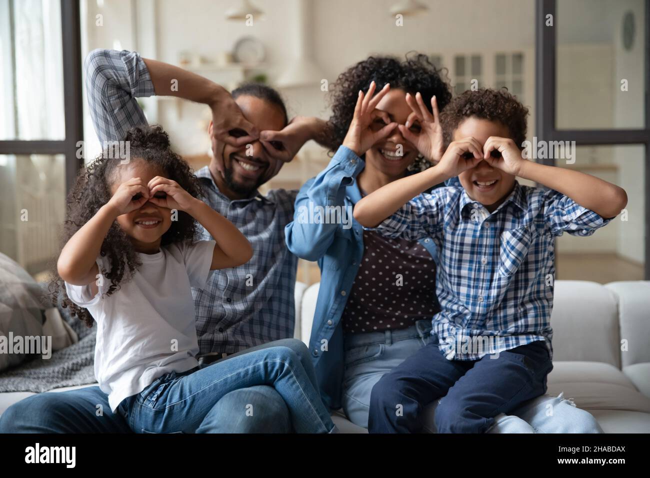 Famille africaine montrant des jumelles avec les doigts sourire regarder l'appareil photo Banque D'Images