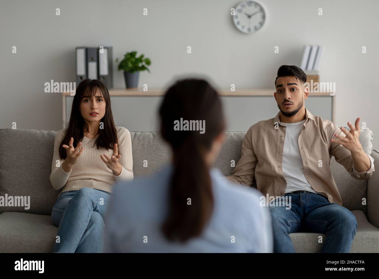 Consultation familiale.Psychothérapeute regardant les conjoints arabes se blâmant les uns les autres pour la crise de relation, vue arrière Banque D'Images