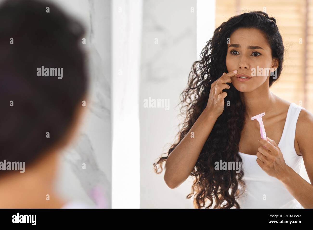 Épilation de la lèvre supérieure.Femme frustrée avec Razor en main regardant le miroir Banque D'Images