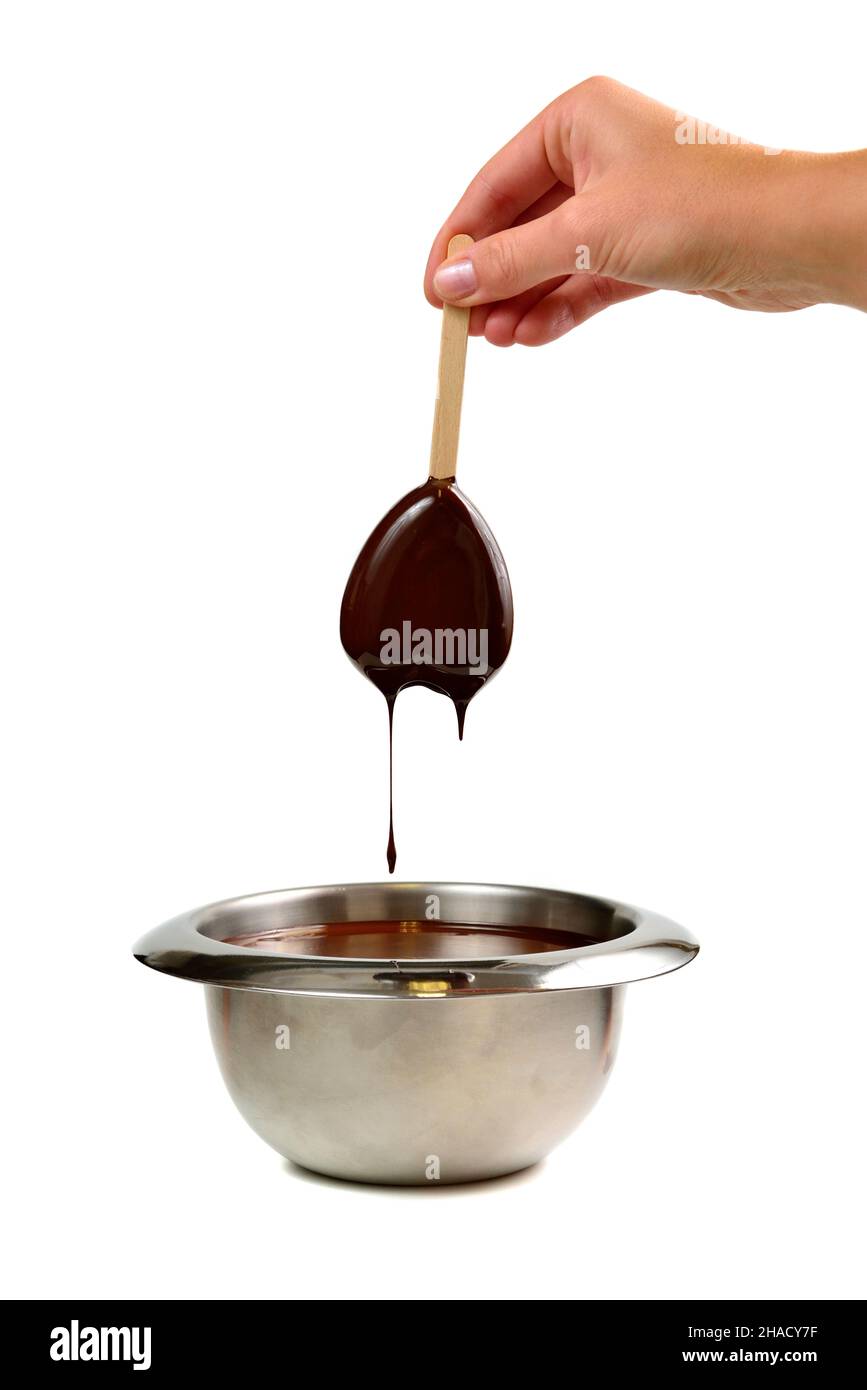 Trempez à la main de la glace à la vanille en forme de coeur sur un bâton de bois dans du chocolat noir liquide chaud Banque D'Images