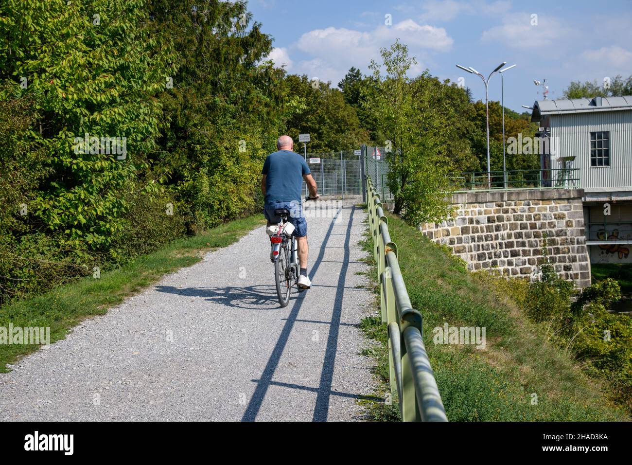 Un cycliste unique avec un vieux vélo et des valises sur une piste cyclable poussiéreuse et non pavée. Banque D'Images