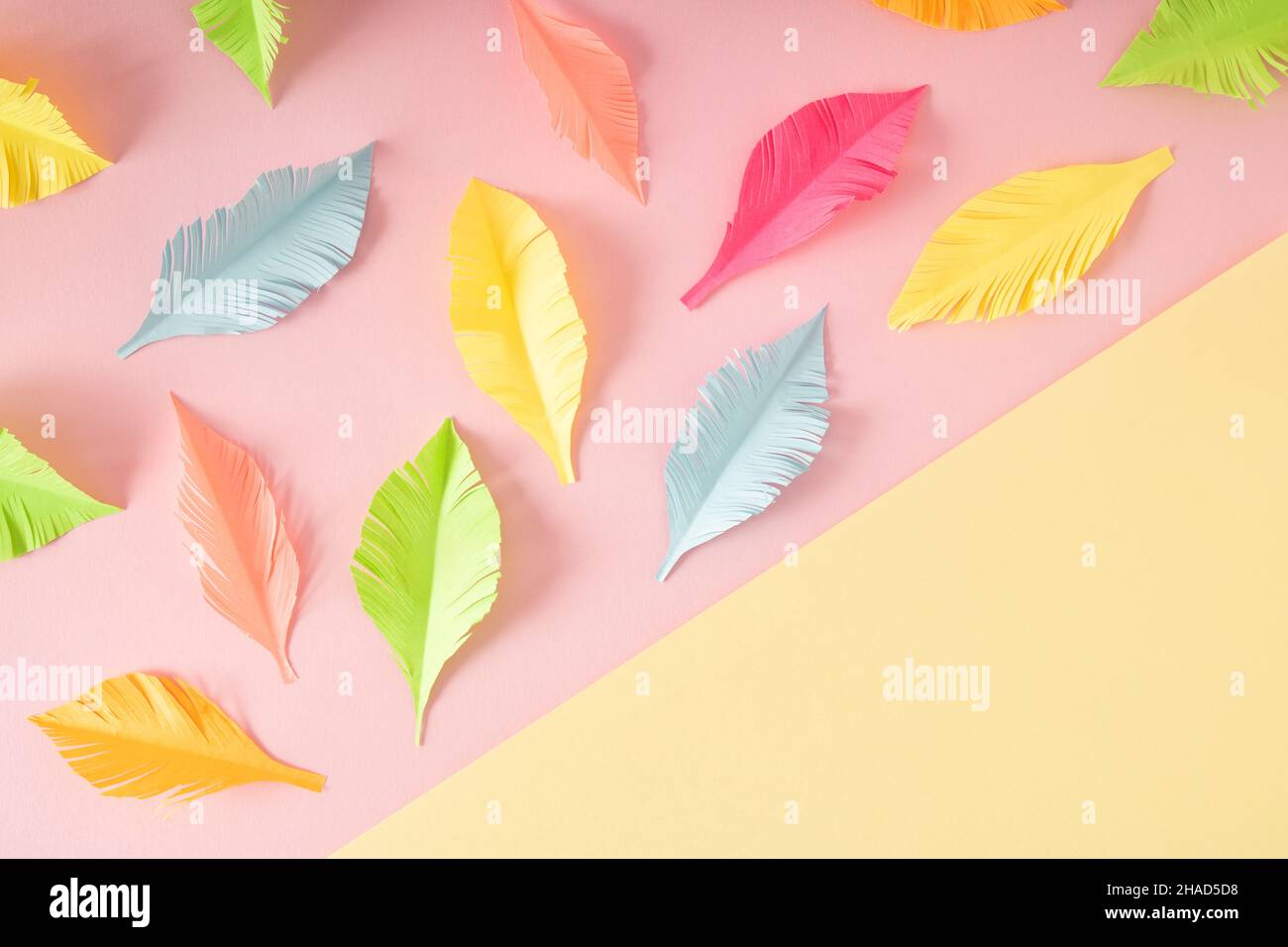 Plumes coupées de couleur pastel sur fond jaune-rose créatif à deux tons.Flat Lay concept coloré. Banque D'Images