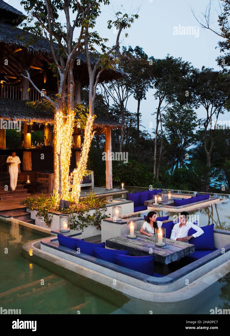 Un couple propose des cocktails au coucher du soleil au salon extérieur, The Den.Six sens Hideaway Yao Noi, Koh Yao Noi, Thaïlande. Banque D'Images
