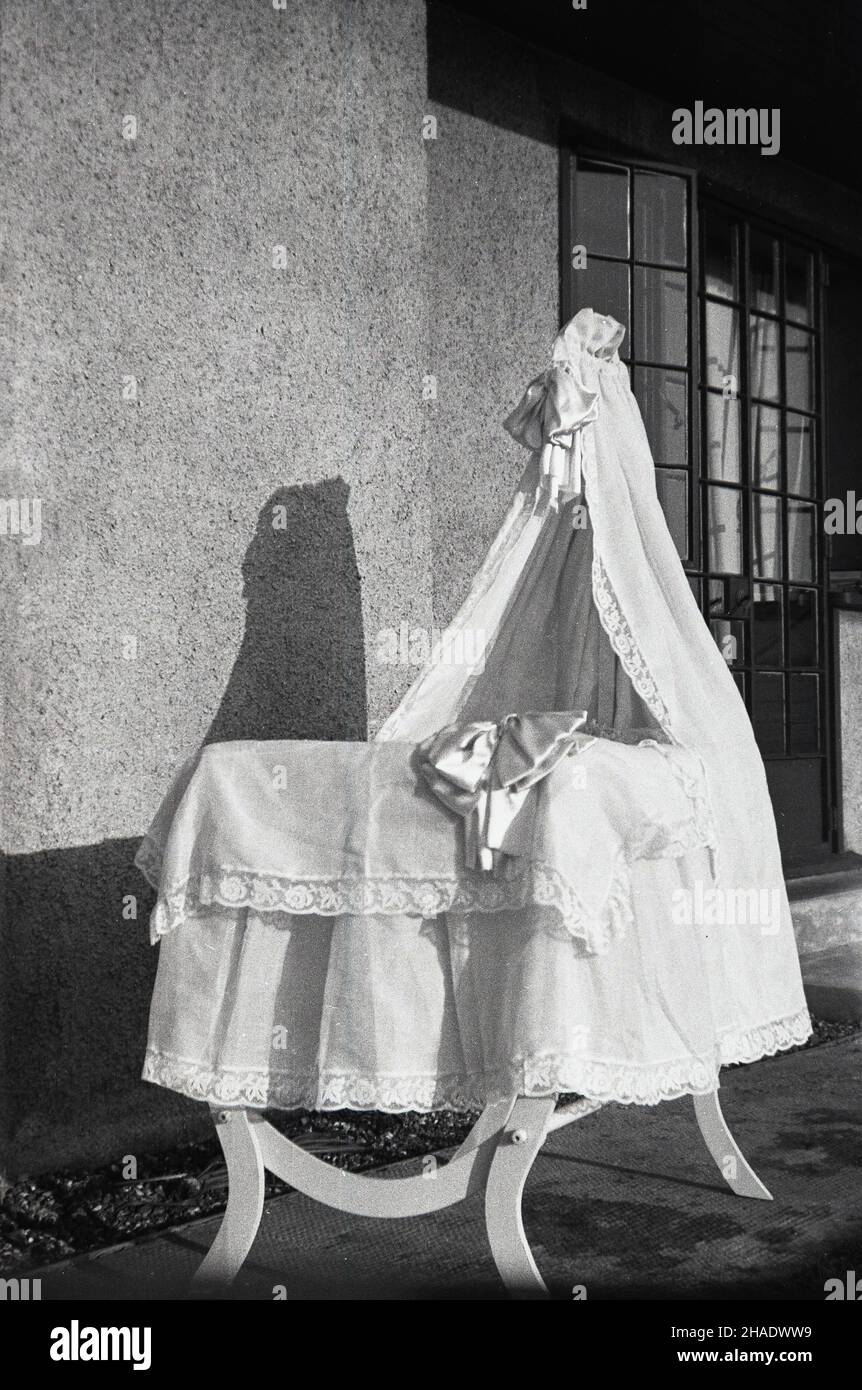 1950s, historique, un lit bébé en bois assis à l'extérieur d'une maison, couvert de literie en dentelle décorée, avec une grande drabe en dentelle ou une verrière à une extrémité, Angleterre, Royaume-Uni. Banque D'Images