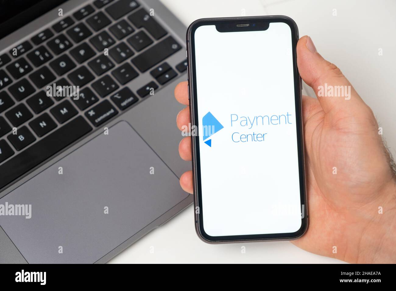 Plate-forme financière du Centre de paiement pour le transfert d'argent à l'aide d'un smartphone.Homme main tenant un téléphone portable avec application sur l'écran et ordinateur portable sur l'arrière-plan.Novembre 2021, San Francisco, États-Unis Banque D'Images