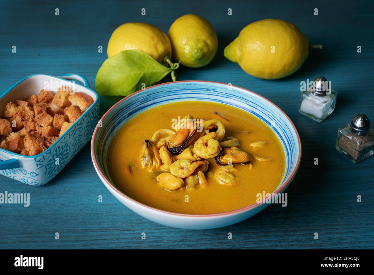 Soupe de fruits de mer à base de crevettes, moules, palourdes, merlu et calmar,servi avec du pain frit et des citrons. Banque D'Images