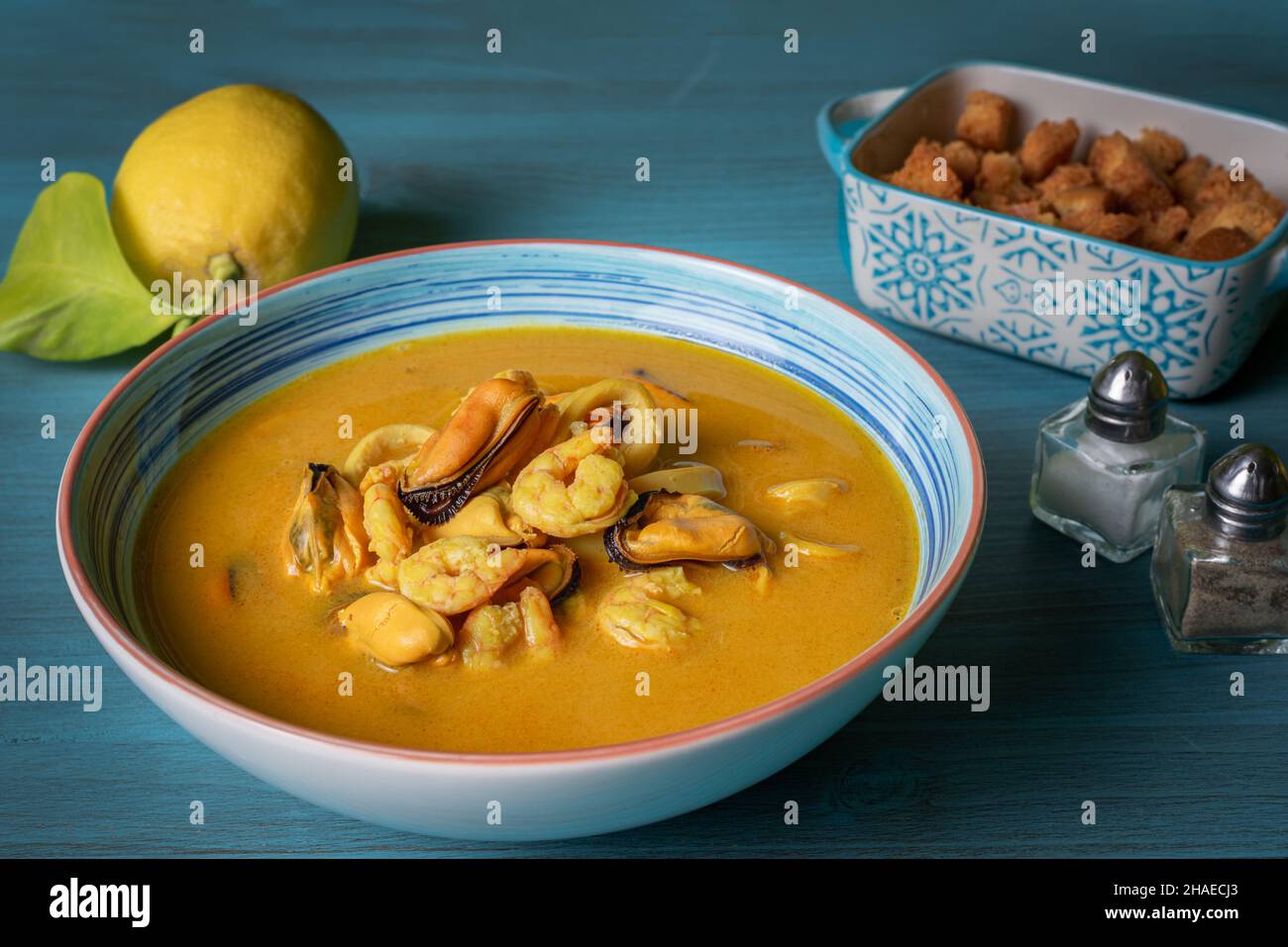 Soupe de fruits de mer à base de crevettes, moules, palourdes, merlu et calmar,servi avec du pain frit et des citrons. Banque D'Images