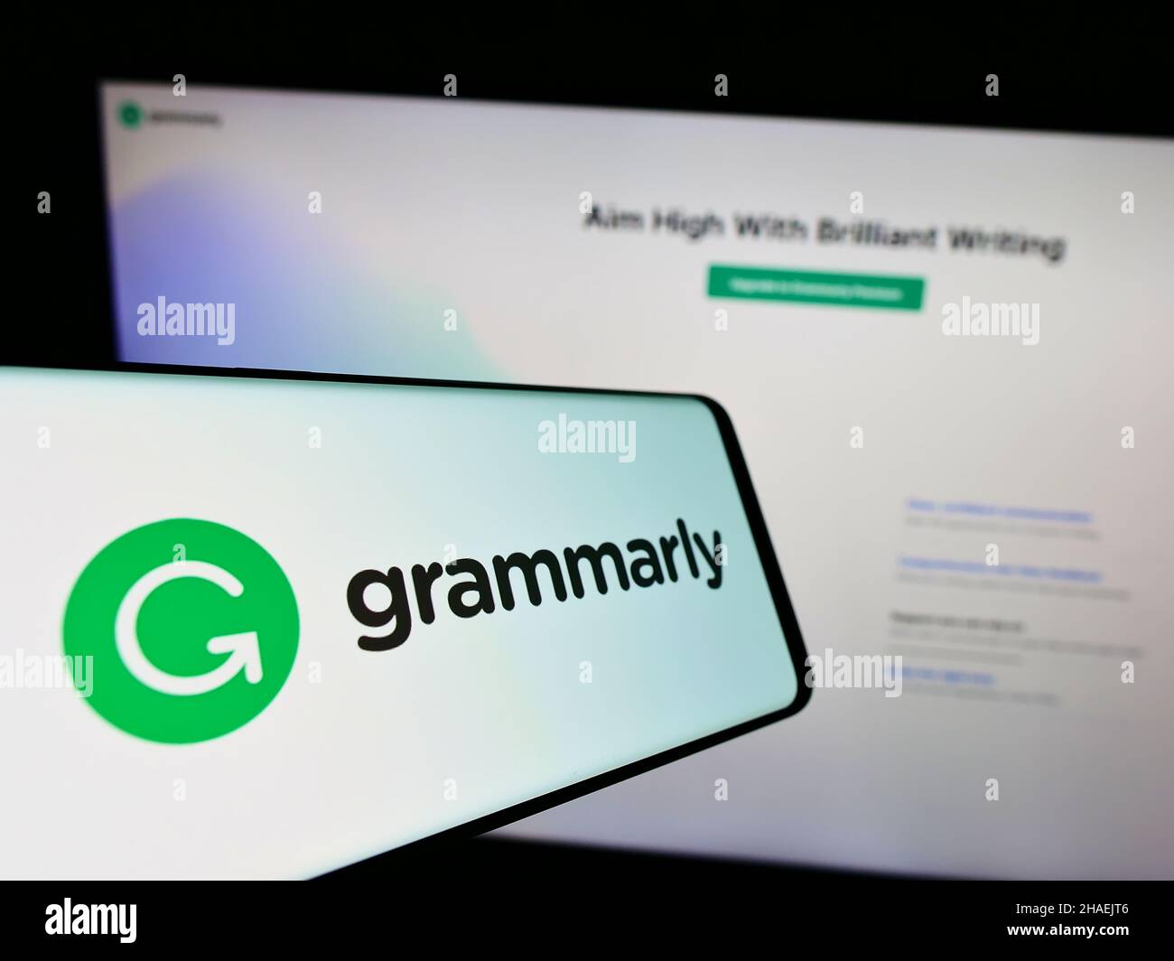 Téléphone mobile avec logo de la société d'aide à la rédaction Grammally Inc. À l'écran en face du site Web d'affaires.Concentrez-vous sur le centre de l'écran du téléphone. Banque D'Images