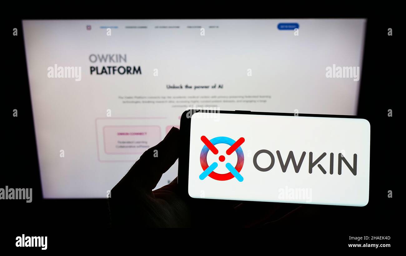 Personne tenant un smartphone avec le logo de la société de recherche médicale américaine owkin Inc. À l'écran devant le site Web.Mise au point sur l'affichage du téléphone. Banque D'Images