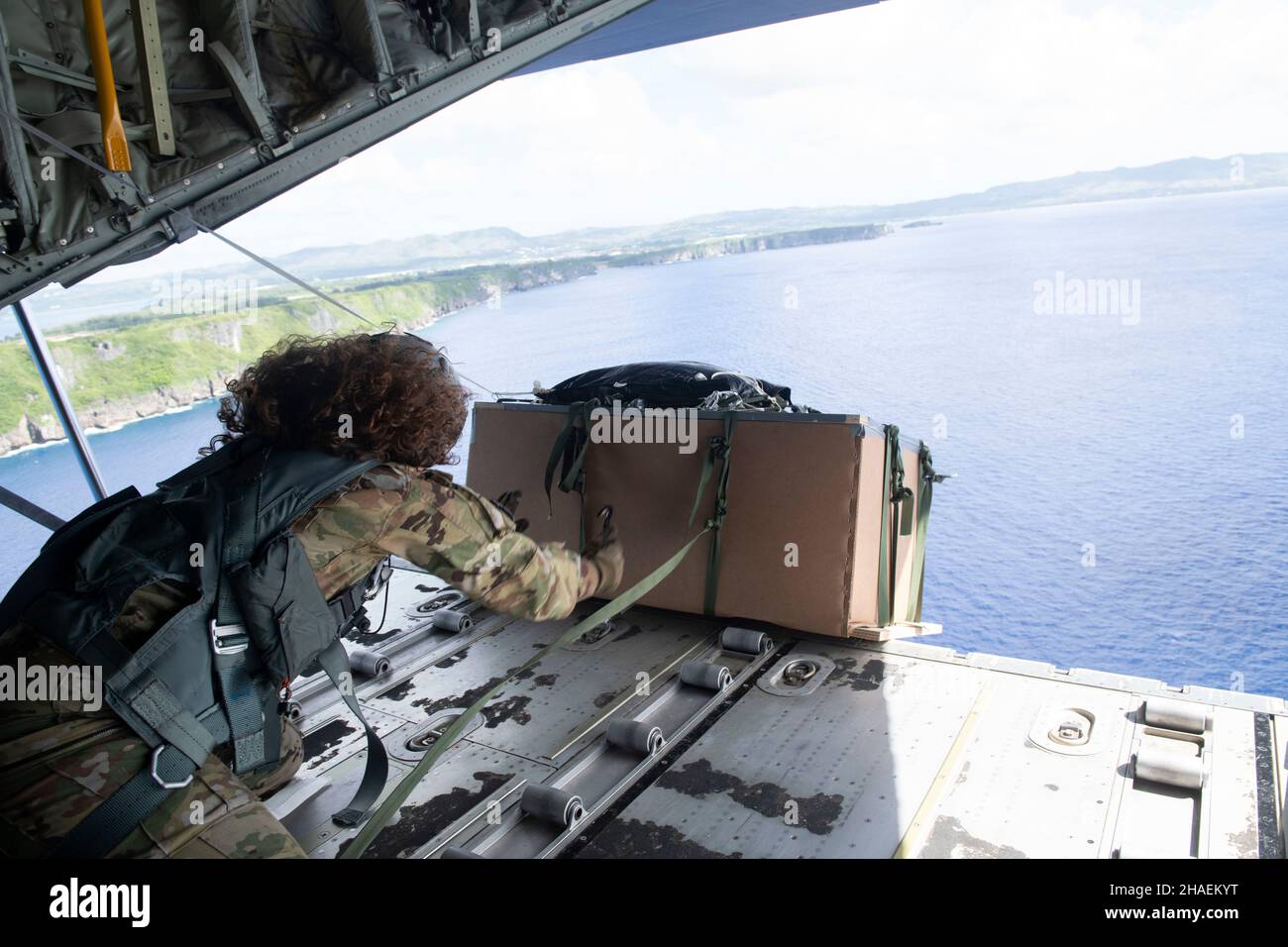 Orote Island, États-Unis.03 décembre 2021.Kim Doyle, chef de l'aviation américaine, charge du 36th escadron de transport aérien, pousse un paquet de cargaison de la baie de chargement d'un avion C130 pendant l'opération annuelle chute de Noël 70th le 3 décembre 2021 au-dessus de l'île d'Orote, à Guam.Chaque année en décembre, les équipages ont fait don de nourriture, de fournitures, de matériel éducatif et d'outils à 55 nations insulaires du Pacifique Sud-est.Crédit : TSgt.Joshua Edwards/US Airforce photo/Alamy Live News Banque D'Images