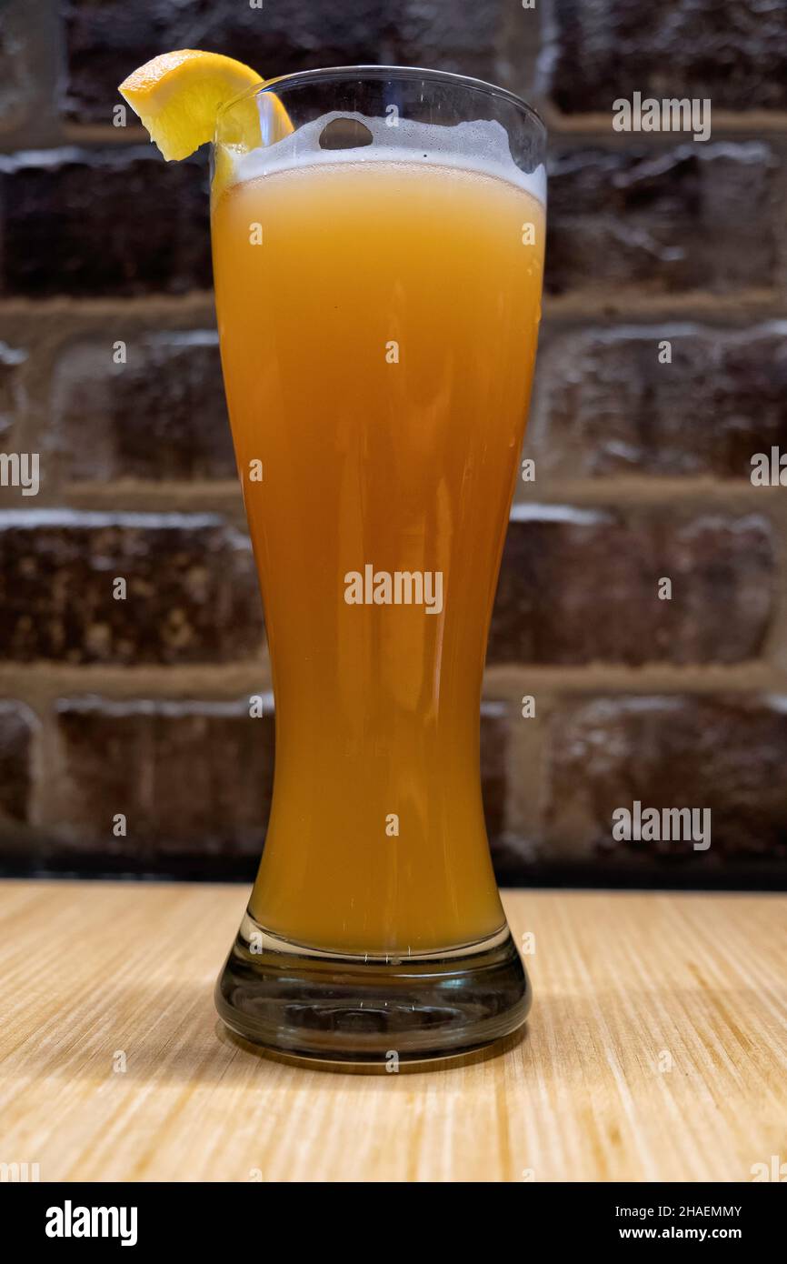 Un verre de bière de blé dans un pub avec un mur de briques en arrière-plan Banque D'Images