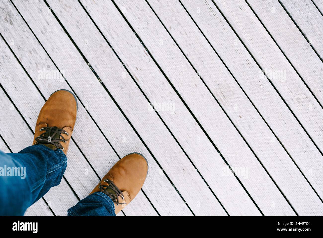 Les pieds mâles en chaussures brunes se tiennent sur un sol en bois blanc.Gros plan Banque D'Images