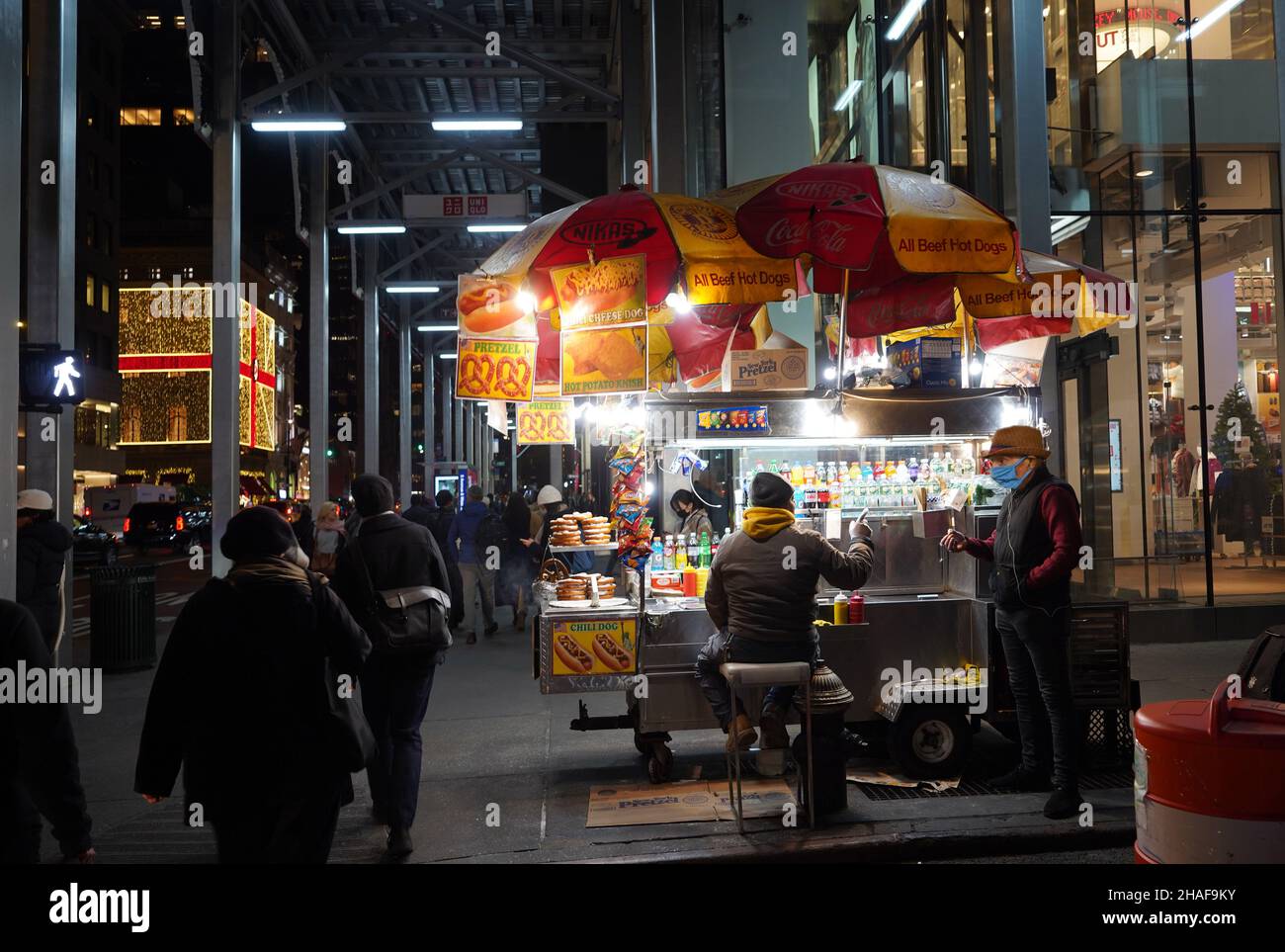 New York, NY - le 16 novembre 2021 : des clients très occupés remplissent le trottoir sur Fifth Avenue malgré la pandémie, passant devant le chariot d'un fournisseur de produits alimentaires. Banque D'Images