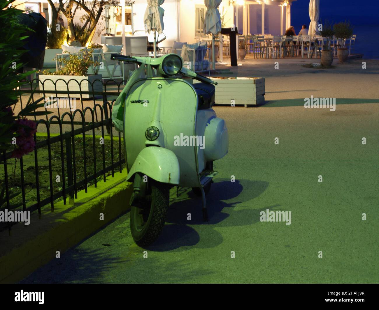 Vespa vert sauge classique garée près de la taverne au bord de l'eau à Kanoni, Corfou, Grèce Banque D'Images