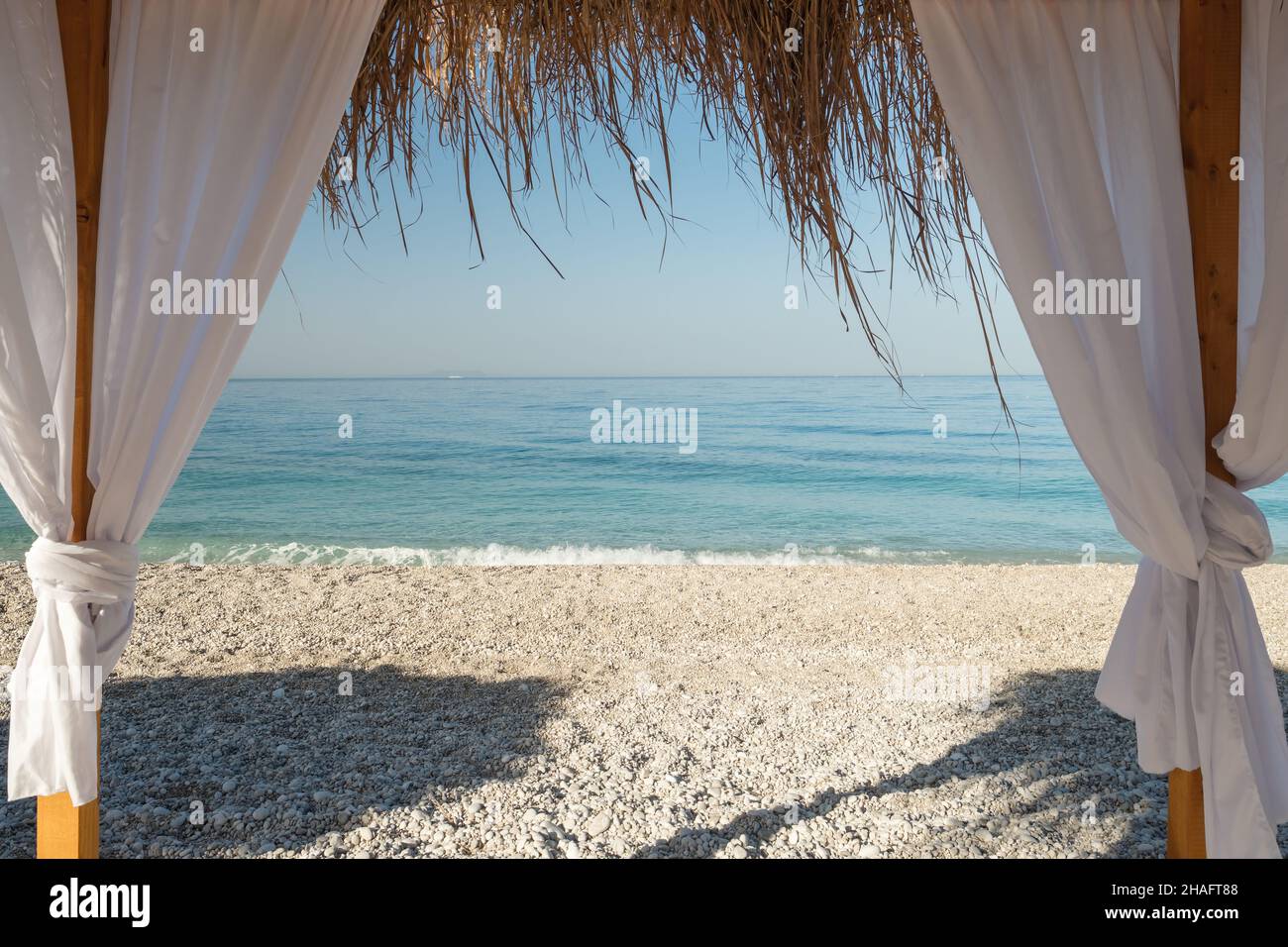 Lit de plage à baldaquin avec rideaux blancs sur la plage de sable Banque D'Images