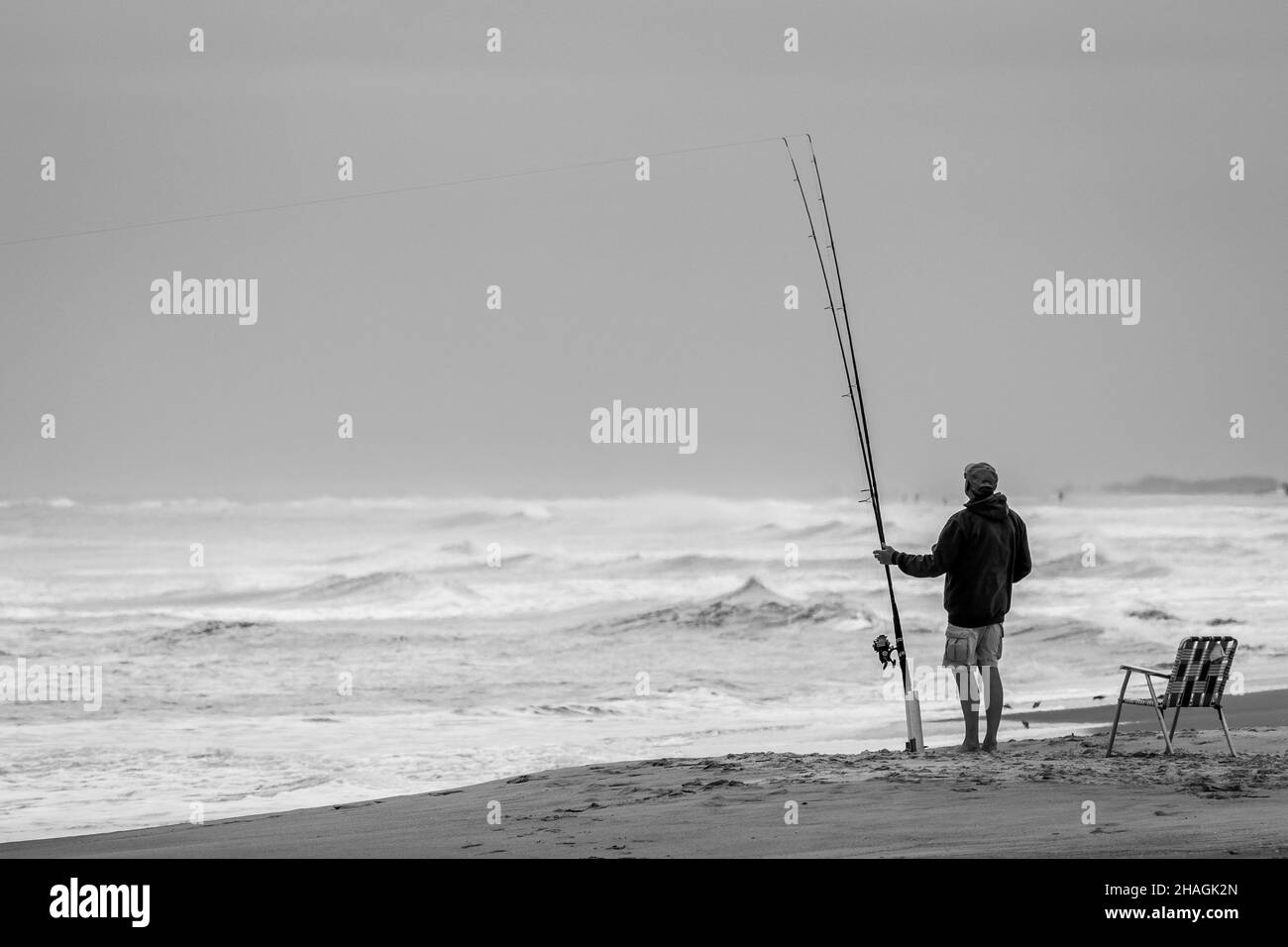 Photo en niveaux de gris d'un pêcheur pêchant dans l'île d'Emerald entourée par l'océan dans le nord de Carolin Banque D'Images Photo en niveaux de gris d'un pêcheur pêchant dans l'île d'Emerald entourée par l'océan dans le nord de Carolin Banque D'Images