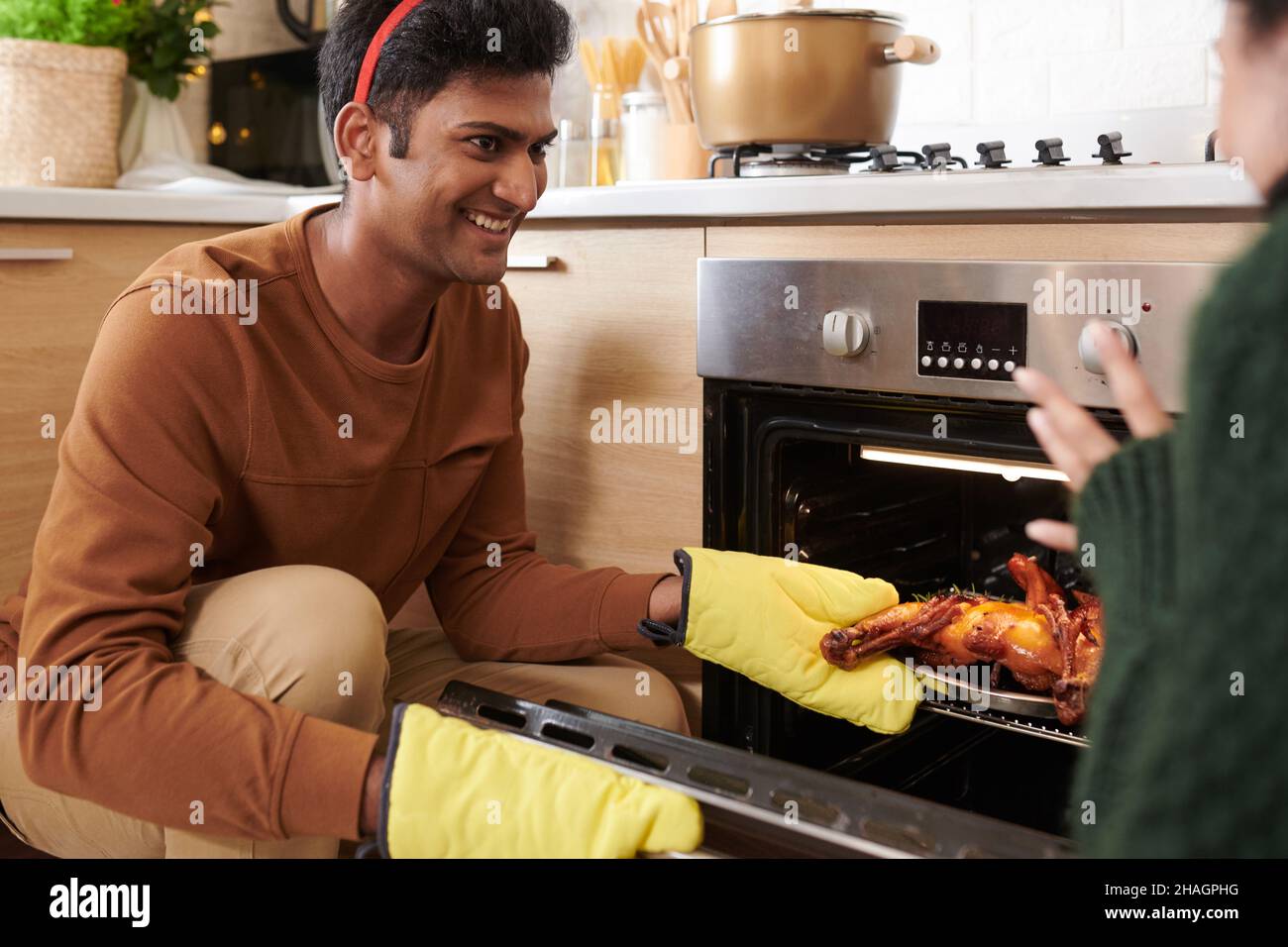 Un jeune homme heureux regardant une petite amie en prenant la dinde, il a cuisiné pour le dîner de Noël hors du four Banque D'Images