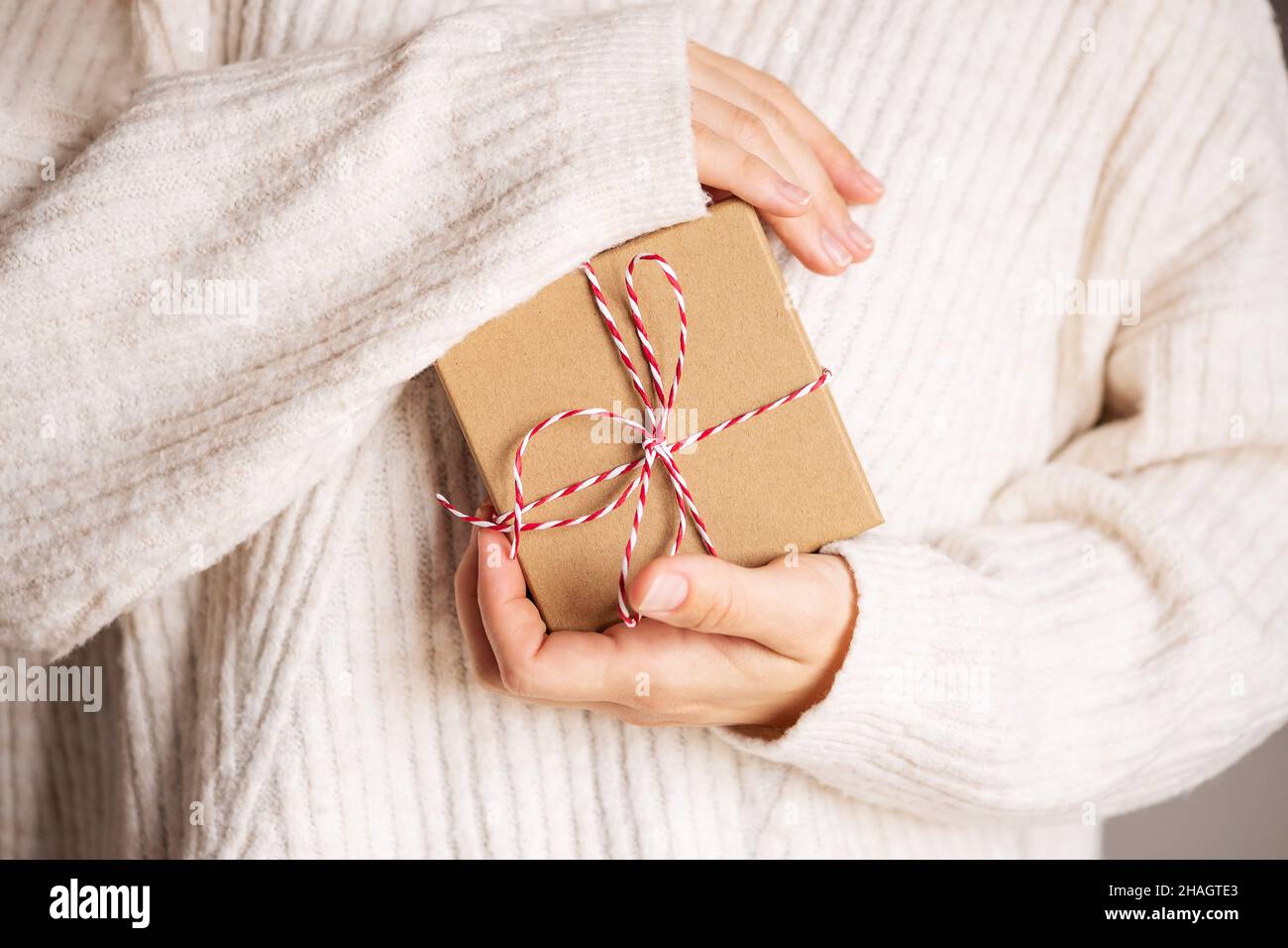 Femme en pull beige confortable donnant des boîtes-cadeaux artisanales de noël avec ruban rouge.Don de cadeaux concept.Valentine jour et de la fête de la mère concept cadeau. Banque D'Images