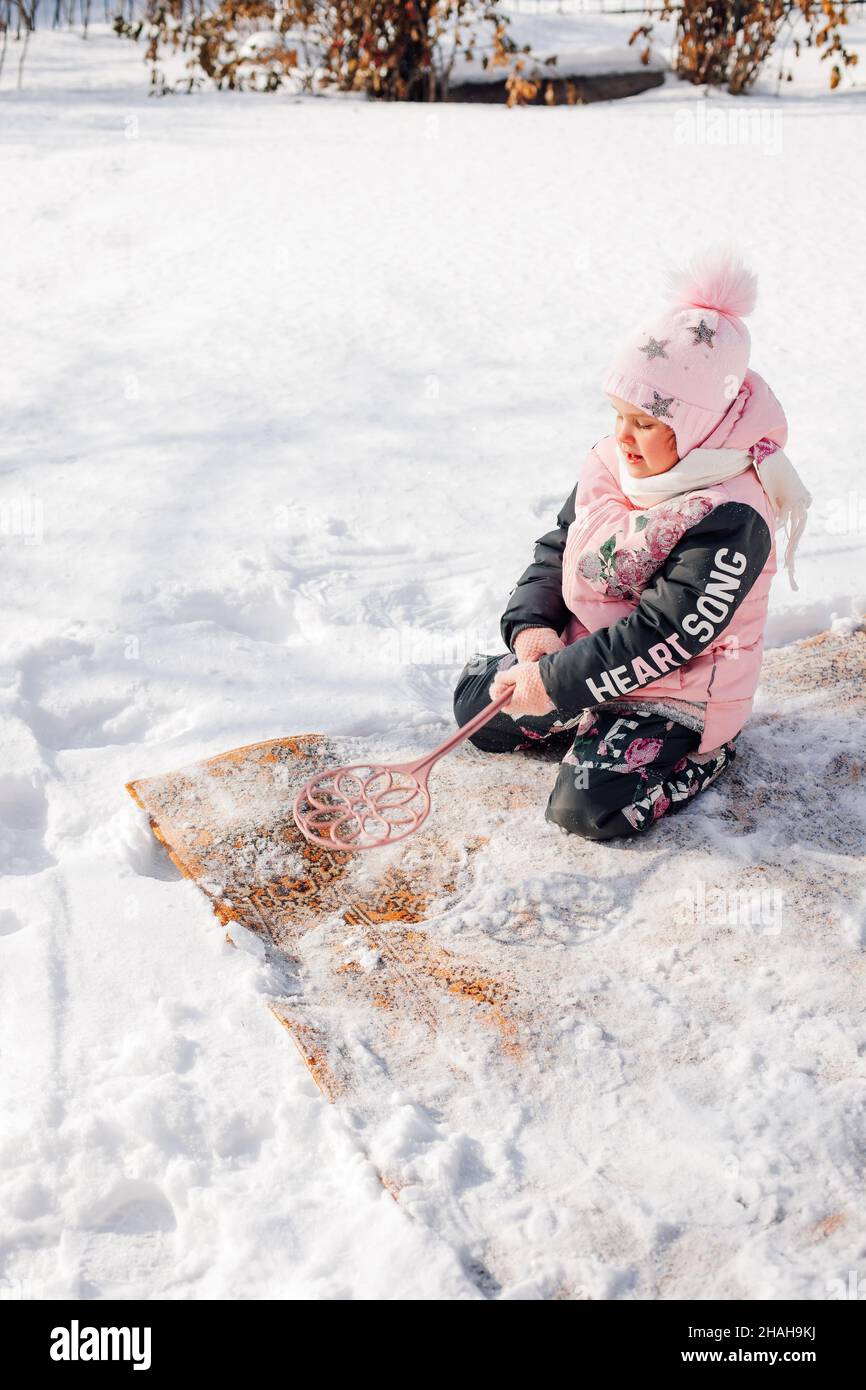 La fille nettoie la moquette par méthode traditionnelle.L'enfant est engagé  dans le nettoyage écologique du tapis persan avec l'aide de la neige  fraîche et le tapis batteur dedans Photo Stock - Alamy
