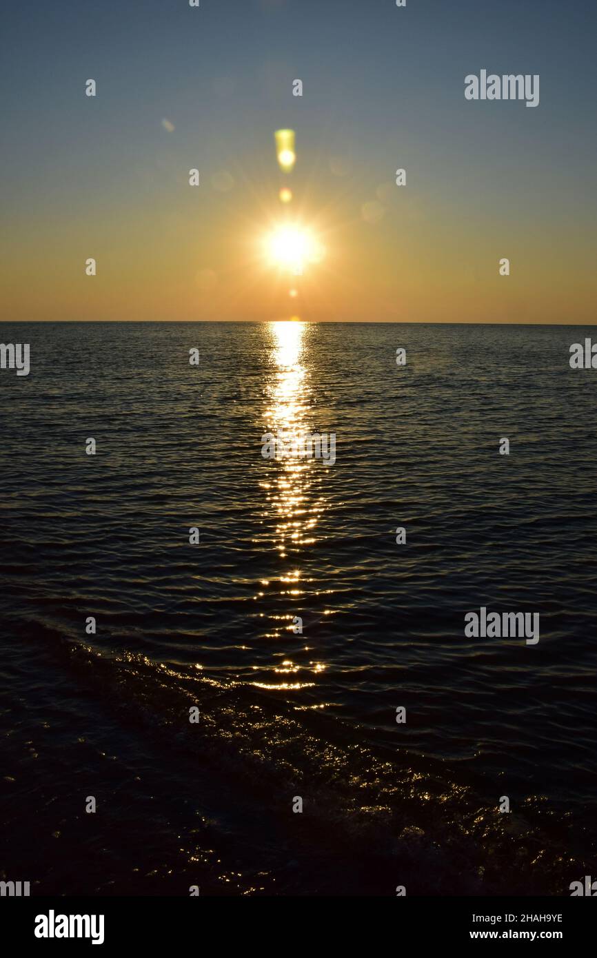 Le matin, le soleil de l'aube sur le fond de la plage de sable de la mer, avec des réflexions sur les vagues calmes Banque D'Images