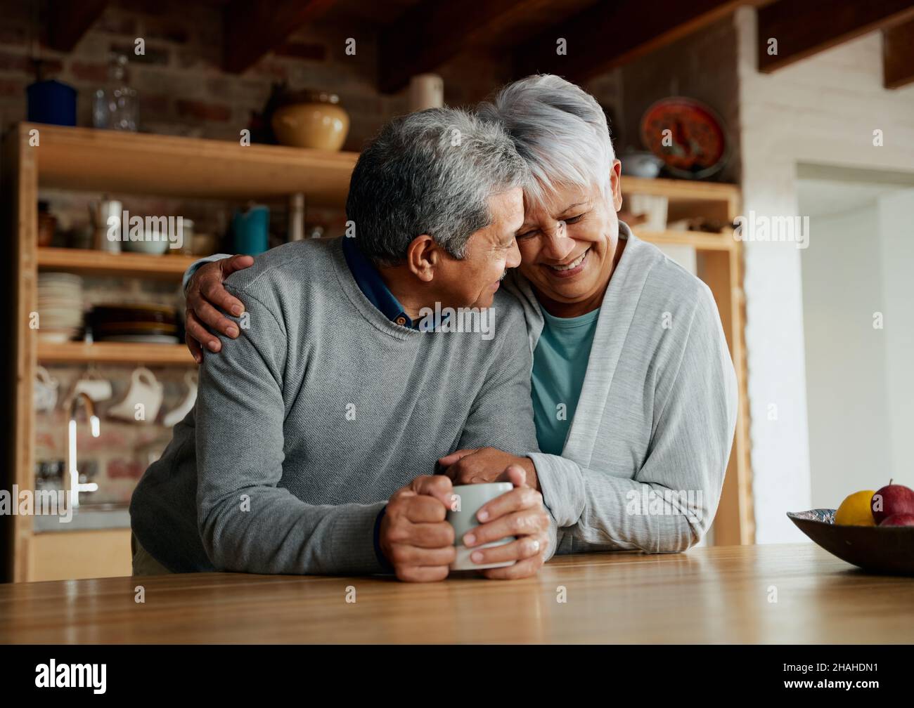 Heureusement, un couple multiculturel âgé à la retraite souriant, se dirige ensemble.Femme tenant mari dans la cuisine moderne. Banque D'Images