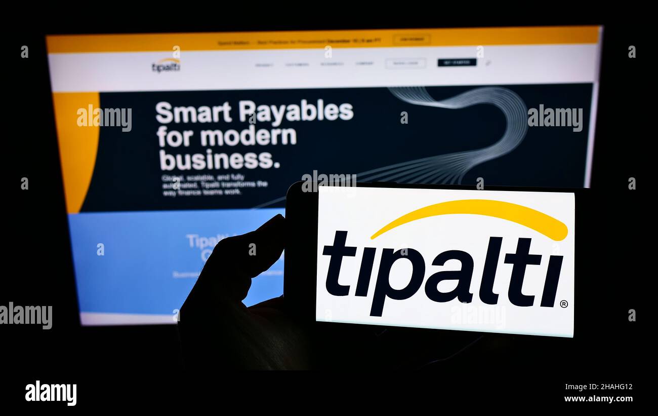 Personne détenant un smartphone avec le logo de la société américaine de logiciels de comptabilité Tipalti Inc. À l'écran devant le site Web.Mise au point sur l'affichage du téléphone. Banque D'Images