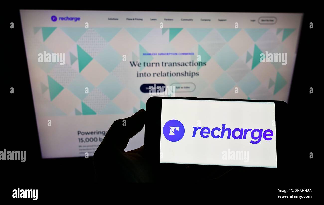 Personne portant un smartphone avec le logo de la société américaine de logiciels d'abonnement recharge Inc. À l'écran devant le site Web.Mise au point sur l'affichage du téléphone. Banque D'Images