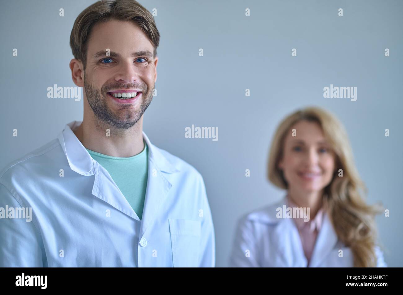 Homme avec un sourire crasseux regardant l'appareil photo et la femme derrière Banque D'Images