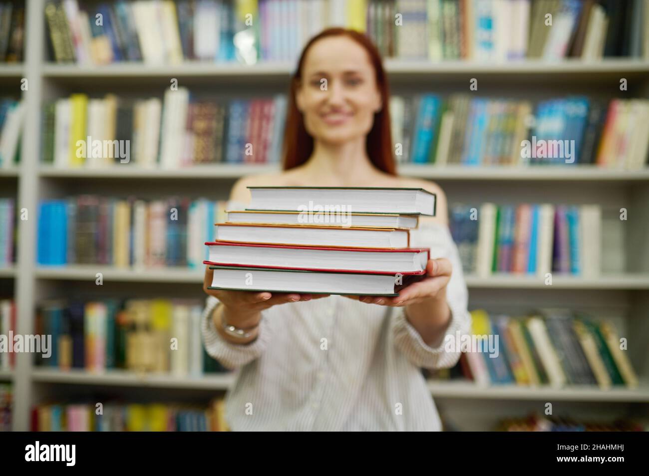 Femme étirant la pile de livres à l'appareil photo Banque D'Images