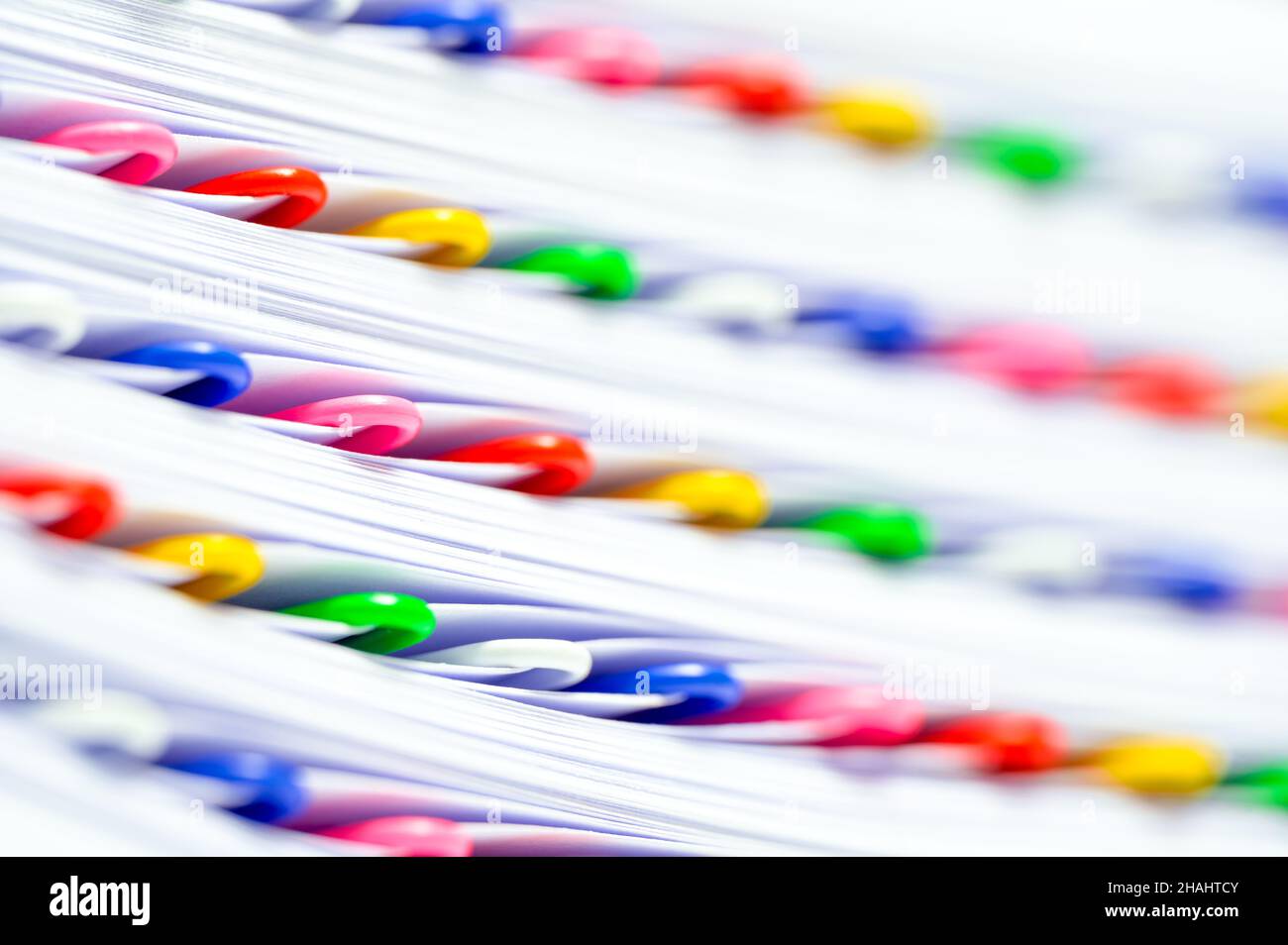 Travail de bureau, bureaucratie ou concept de paperasserie.Trombones colorés dans une pile de fichiers et de papiers. Banque D'Images