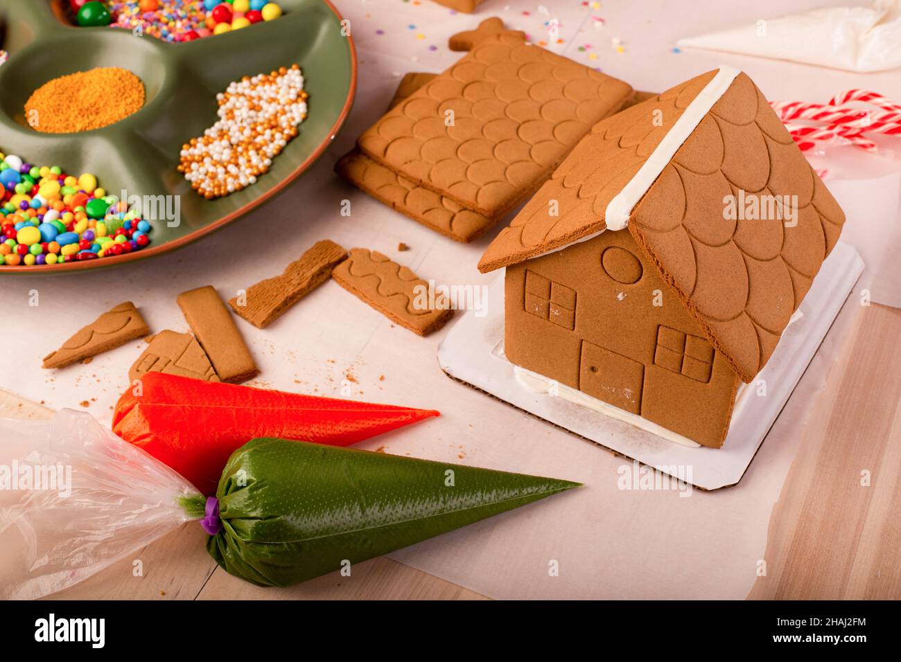 Les enfants assemblent et décorent une maison de pain d'épice à l'heure de Noël.Tradition familiale de Noël, artisanat de Noël. Banque D'Images