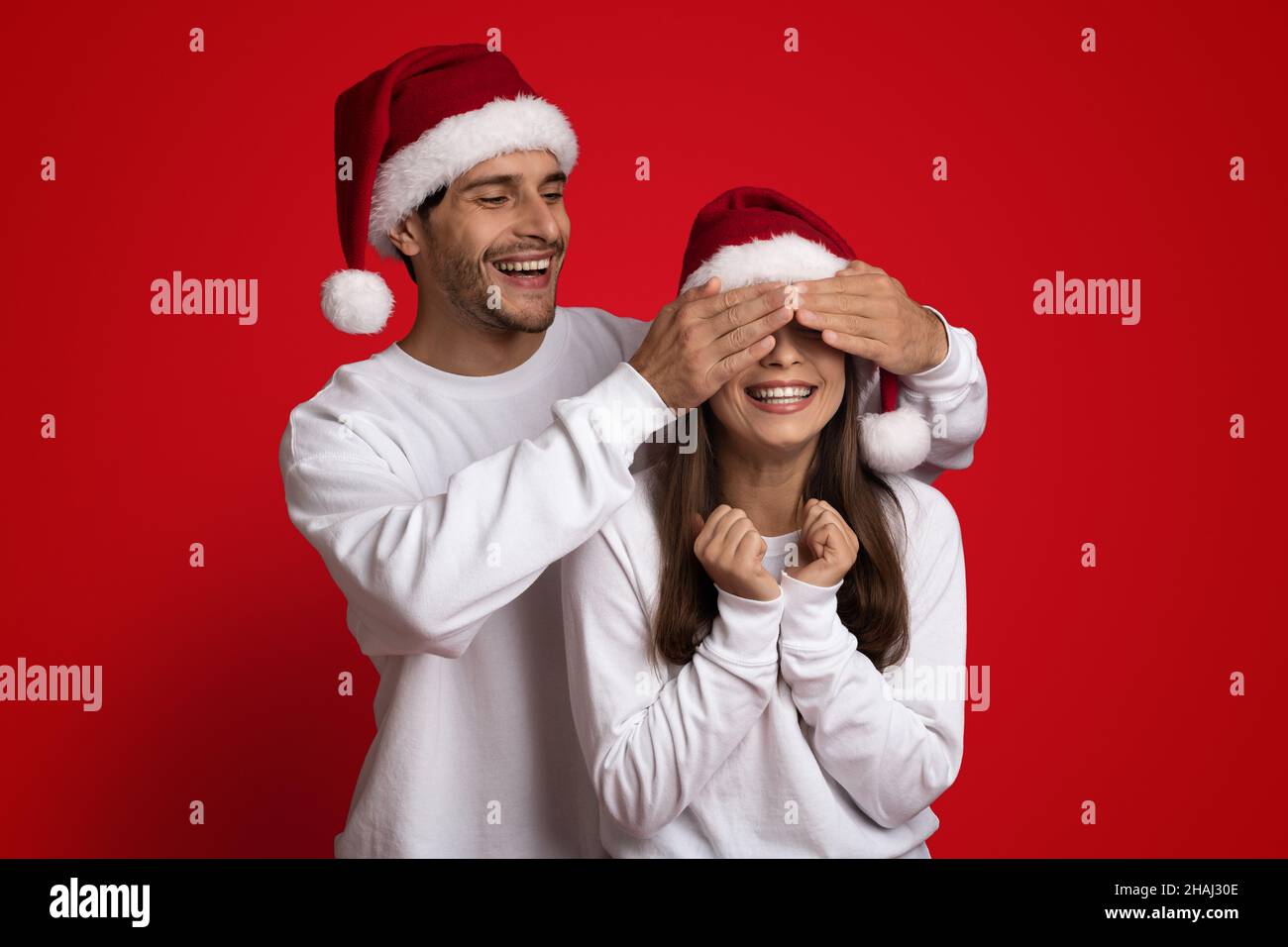 Devinez qui.Joueur Guy en chapeau de père Noël couvrant les yeux de petite amie avec les mains Banque D'Images