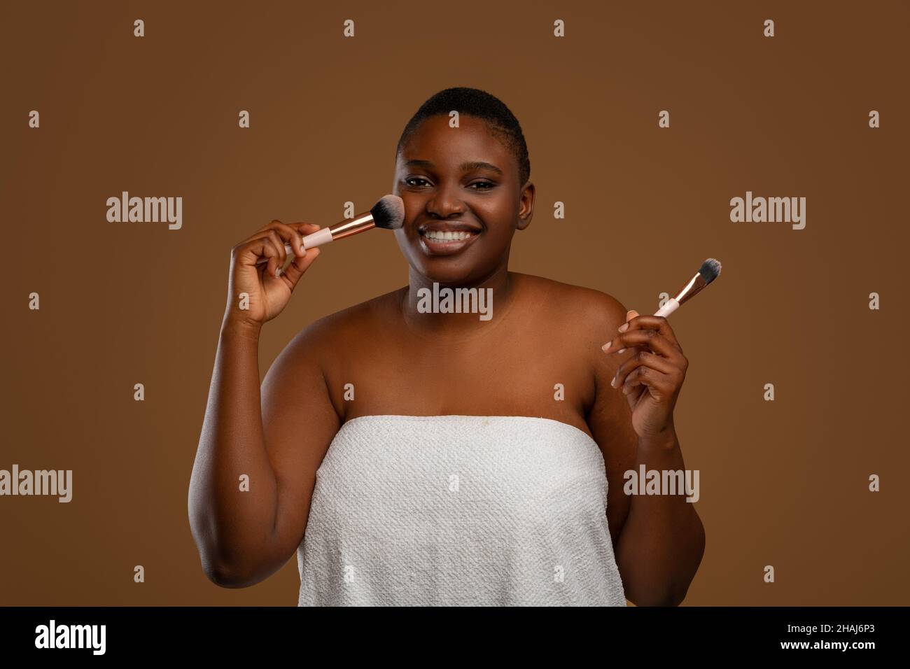 Portrait d'une belle femme de chubby noire avec pinceau à maquillage Banque D'Images