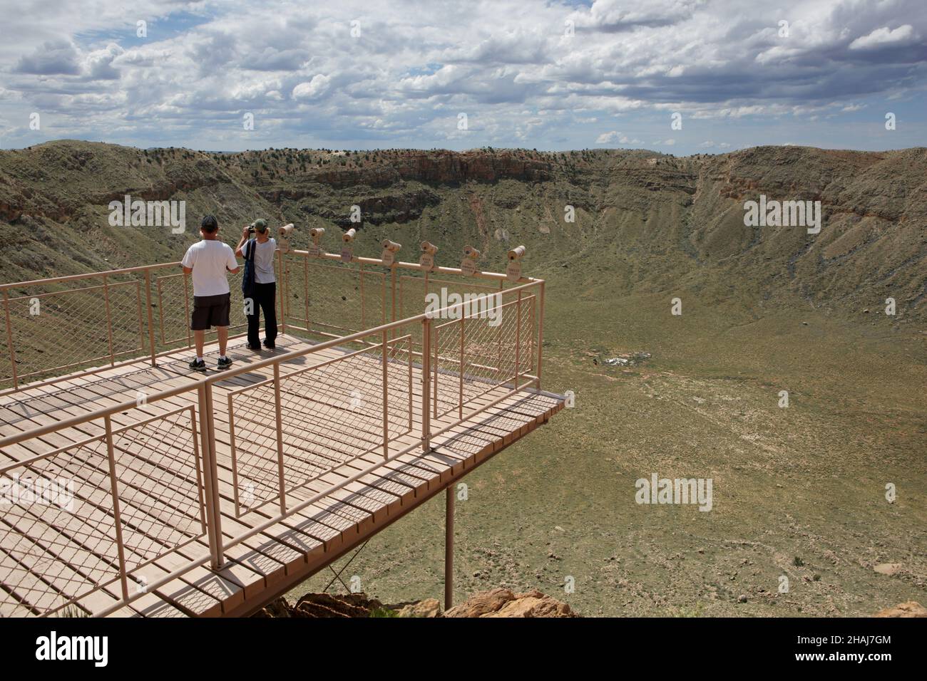 Deux personnes se tenant près des télescopes sur le pont d'observation du Meteor Crater près de Winslow dans le nord de l'Arizona, aux États-Unis.Le bord du cratère est renversé, couché Banque D'Images