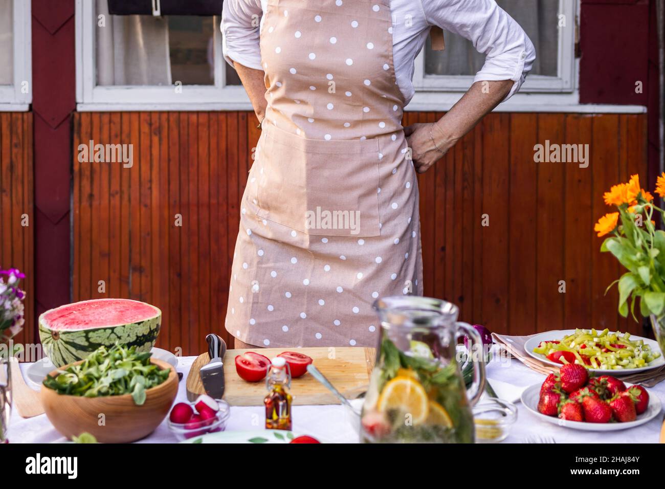 Femme attachant son tablier et se préparer à cuisiner.Préparer des aliments frais et sains pour la fête en plein air Banque D'Images
