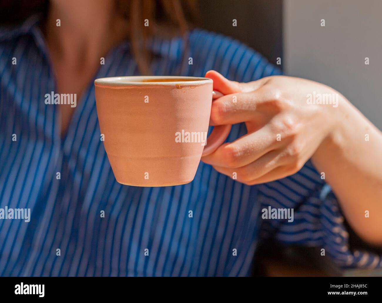 Une femme tient une tasse de café près. Banque D'Images