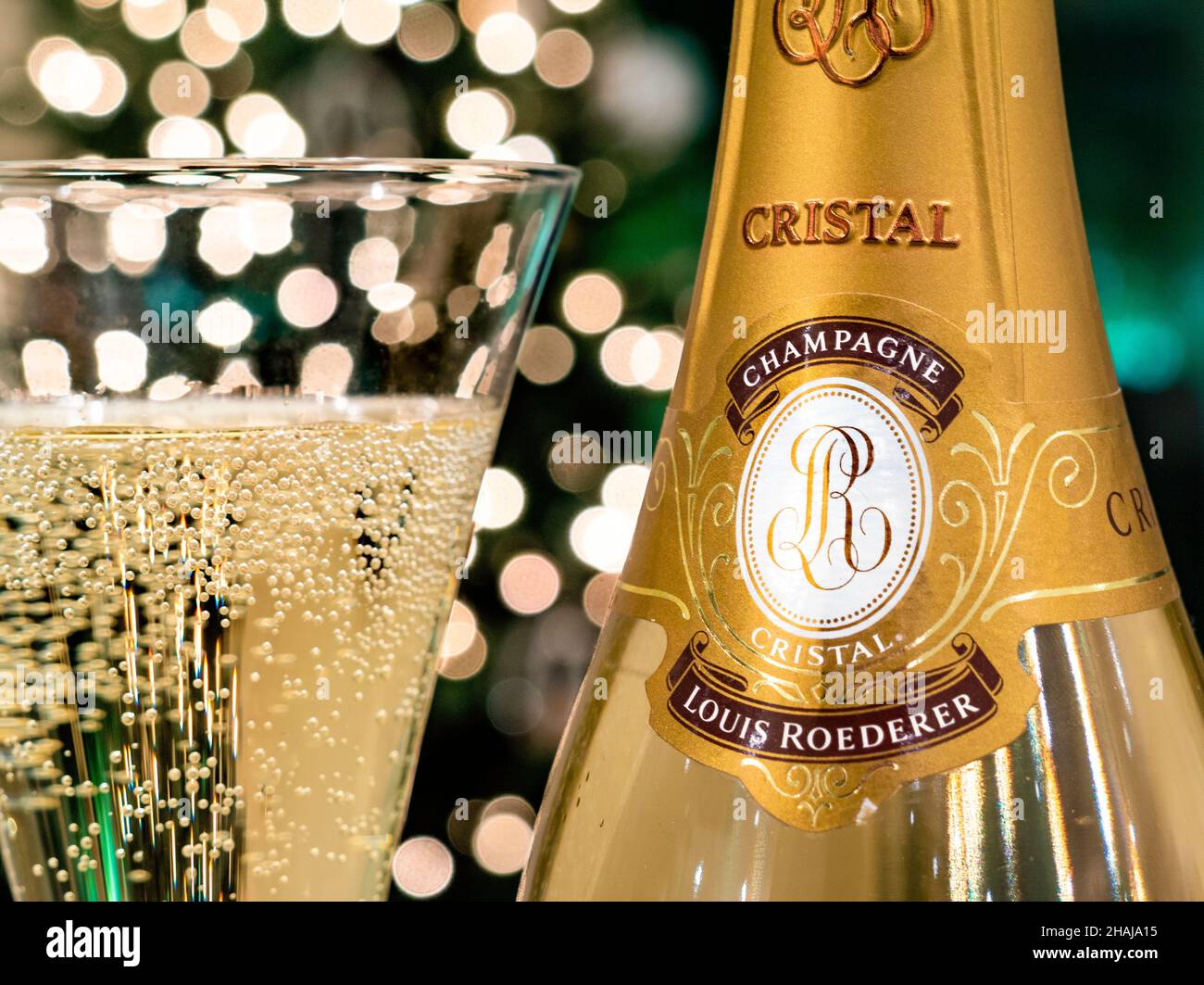 Bouteille DE CHAMPAGNE CRISTAL et verre de champagne de luxe Louis Roederer Cristal fraîchement versé avec lumières étincelantes pour les fêtes en arrière-plan Banque D'Images