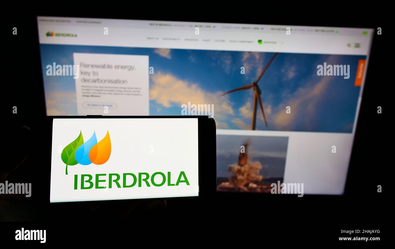 Personne tenant un smartphone avec le logo de la société espagnole d'électricité Iberdrola S.A. à l'écran devant le site Web.Mise au point sur l'affichage du téléphone. Banque D'Images