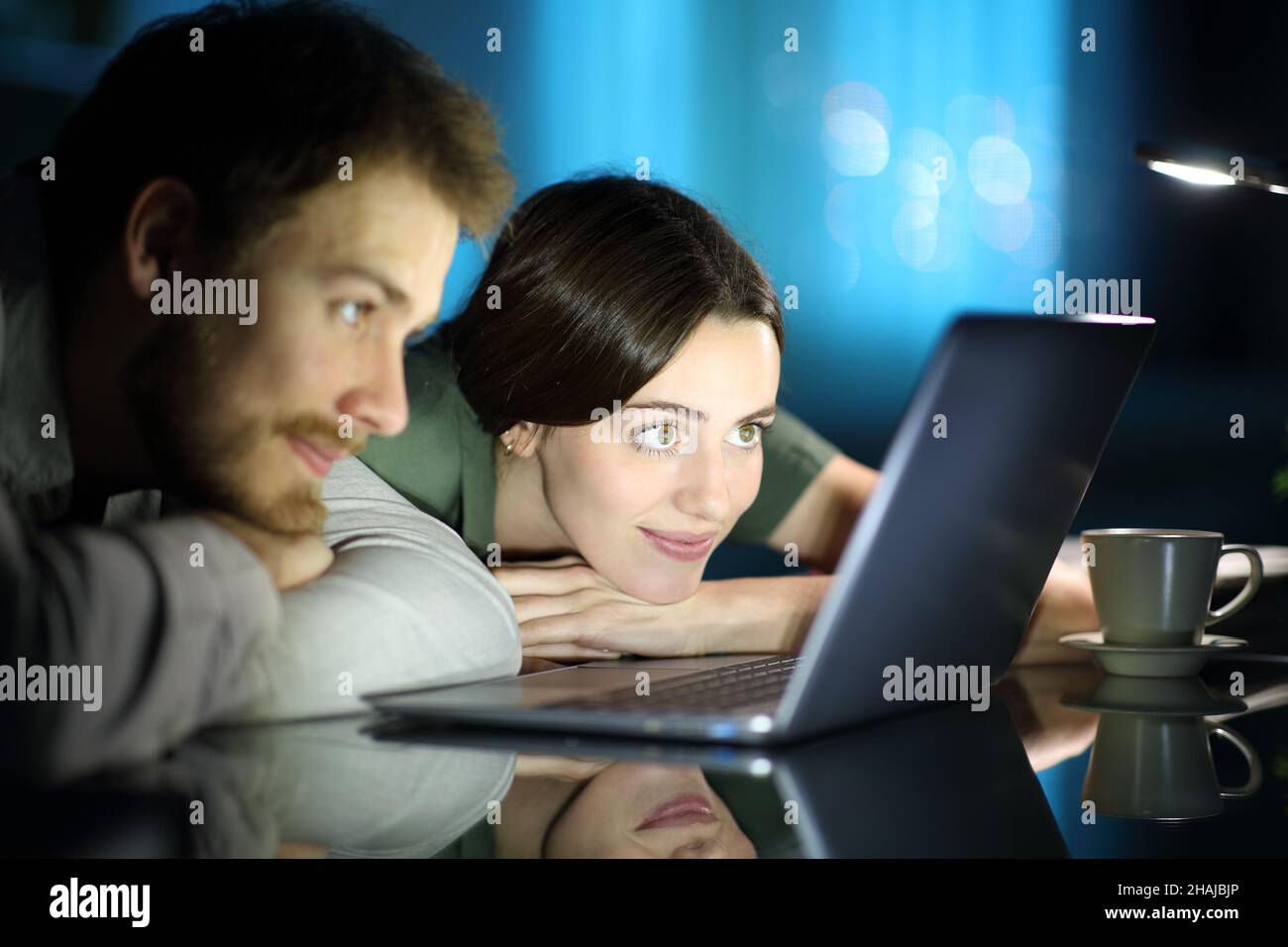 Couple regardant du contenu multimédia sur un ordinateur portable dans la nuit à la maison Banque D'Images